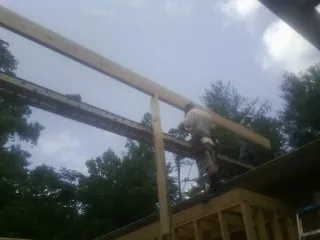 Carpenter setting a ridge beam over a new addition frame — Ice Dam Removal by Roofing Brothers in Arch Cape