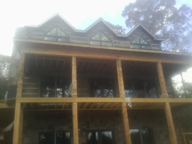 Dormers and porch framing on a large log home under construction — Roof Coating work by our crew in Arch Cape