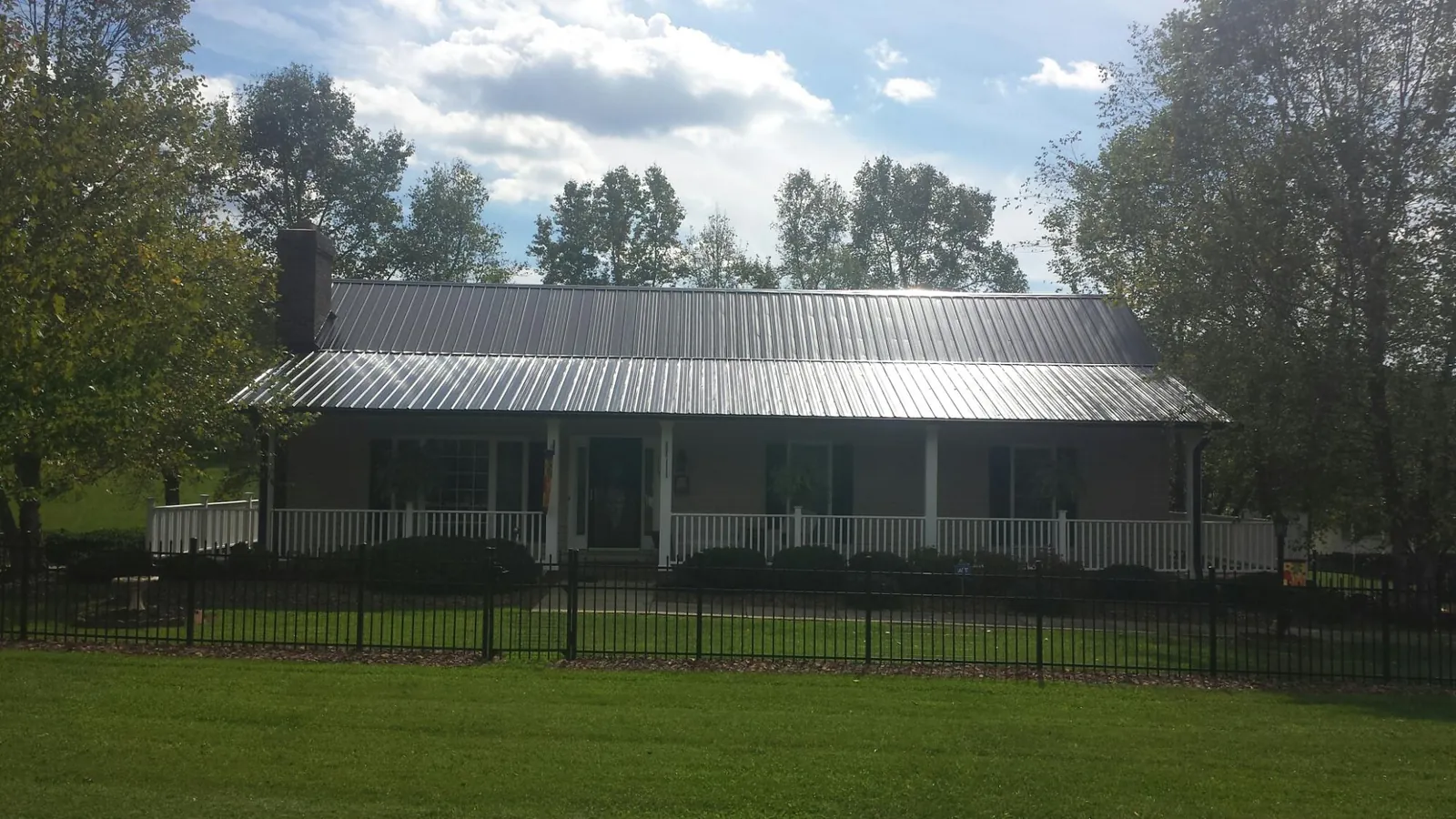 Gray metal roof on a brick ranch with a full width front porch — Gutter Guard Installation work by our crew in Arch Cape