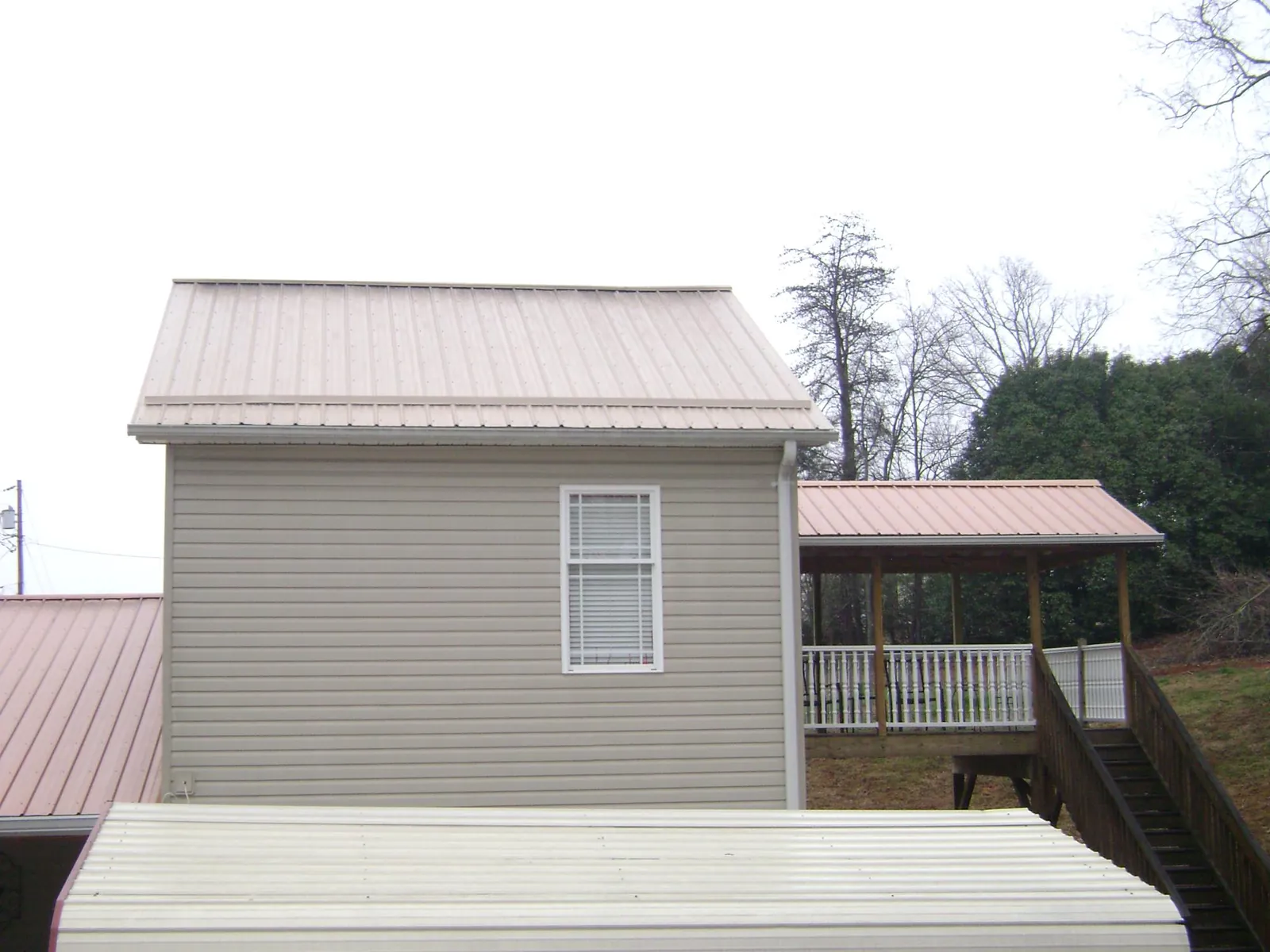 Tan metal roofs on a two story addition and attached porch, from a Roof Replacement job in Arch Cape