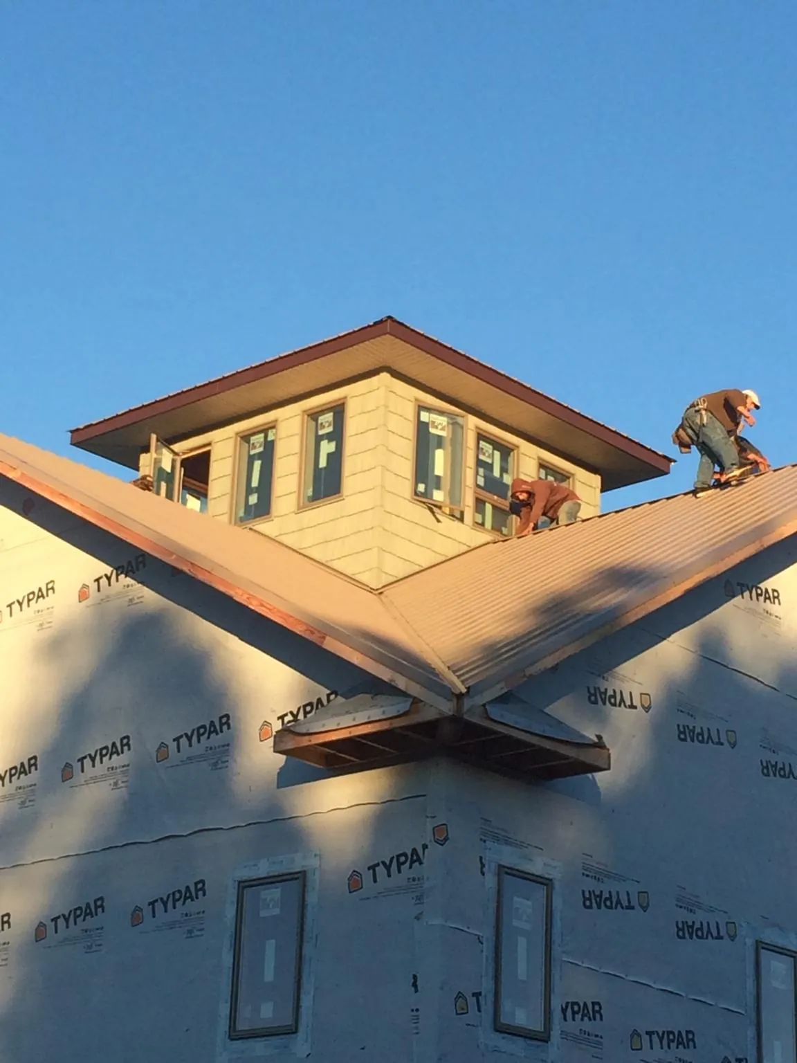 Roofers working around a rooftop cupola on a new metal roof at sunset — Roof Waterproofing in Arch Cape by Roofing Brothers